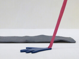 Flache Hand aus Ton an der ein Band befestigt ist, im Hintergrund eine Landebahn aus Pappmache. 