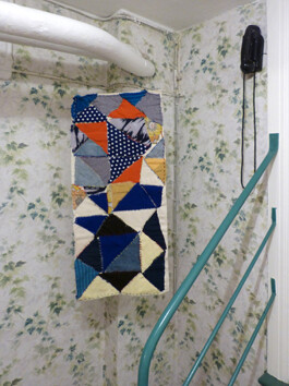 Kunstwerk aus Stoff mit geometrischem Muster im Ausstellungsraum.