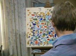 Filmstill von einem Maler in Rückenansicht vor einem abstrakten Bild.