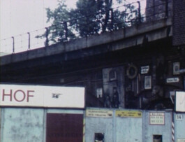 Filmstill der Berlin in den 80er Jahren zeigt. Die Aufnahme entstand neben einem S-Bahn Gleis.