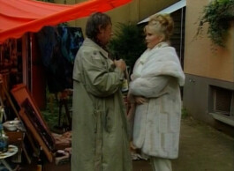 Filmstill von einem Mann und einer Frau, die sich gegenüber stehen.