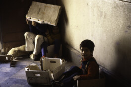 Kinder, die mit Kisten in einem Hausflur spielen.