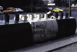 Fotografie von Glascontainern. Auf einem davon steht