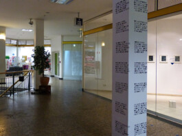 Ausgedruckte Texte sind auf eine Säule geklebt.