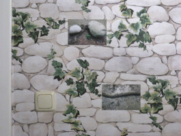 Fotos von Steinen hängen auf einer Tapete mit Stein-Muster.