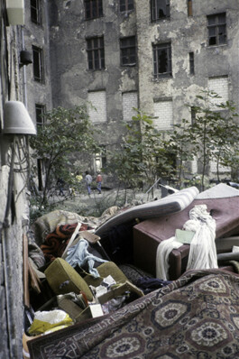 Ein Innenhof in dem Müll liegt, im Hintergrund sind Kinder zu sehen.