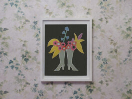 Eine gerahmte Collage, die Stiefel zeigt, die als Blumenvasen genutzt werden, hängt an einer Efeu-Tapete.