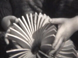 Filmstill von einem Geometrischen Objekt, das von einem Kind gehalten wird.