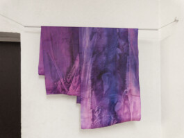 Lilafarbene Papierbahnen hängen über einer Stange.