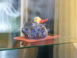 Getöpferter Vogel in einer Vitrine.