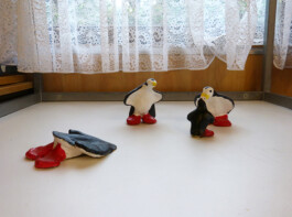 Pinguin Skulpturen stehen auf einem Tisch.