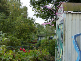 Eine rosafarbene Skulptur aus Metall ist an einem Bauwagen befestigt.
