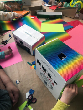 Kinder bauen eine Stadt aus Schachteln und Pappe.