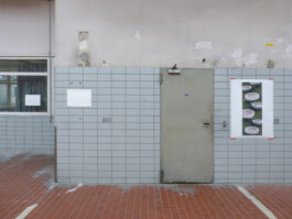 Zeichnungen und eine Fotogarafie präsentiert an der Wand einer ehemaligen Autowerkstatt.