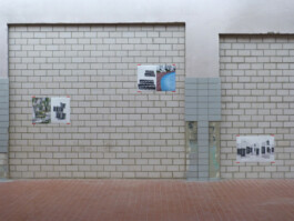 Fotografien von Gebäuden, präsentiert an Wänden einer ehemaligen Autowerkstatt.