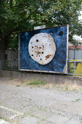 Plakatwand mit einem Poster, das ein Fladenbrot zeigt.